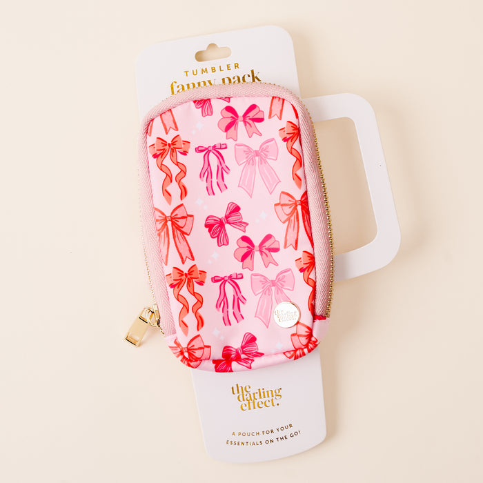 The Blushing Bows Tumbler Fanny Pack by the-darling-effect features a pink design with red and pink bow patterns and a zipper. It's shown on its packaging labeled "Tumbler Fanny Pack" and "the-darling-effect.
