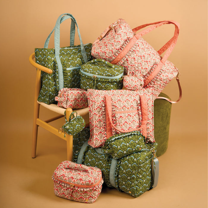 A variety of quilted bags and pouches from The Darling Effect, including the Everbloom Dusty Rose On-the-Go Quilted Weekender Bag with an adjustable shoulder strap, features green and pink floral patterns on backpacks, totes, duffels, and small cases.