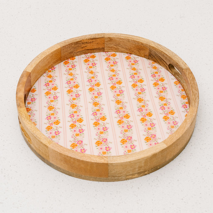 The Petal Parade Pink Large Round Wood Enamel Tray by the-darling-effect features a floral and striped base in pink and orange, making it a charming bamboo serving tray for any occasion.