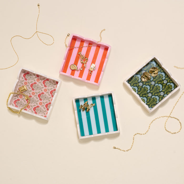 Four Sicily Stripes Pink Scallop Trinket Trays by The Darling Effect display gold necklaces, bracelets, and earrings on a light beige background, with gold chains draped around each organizer.