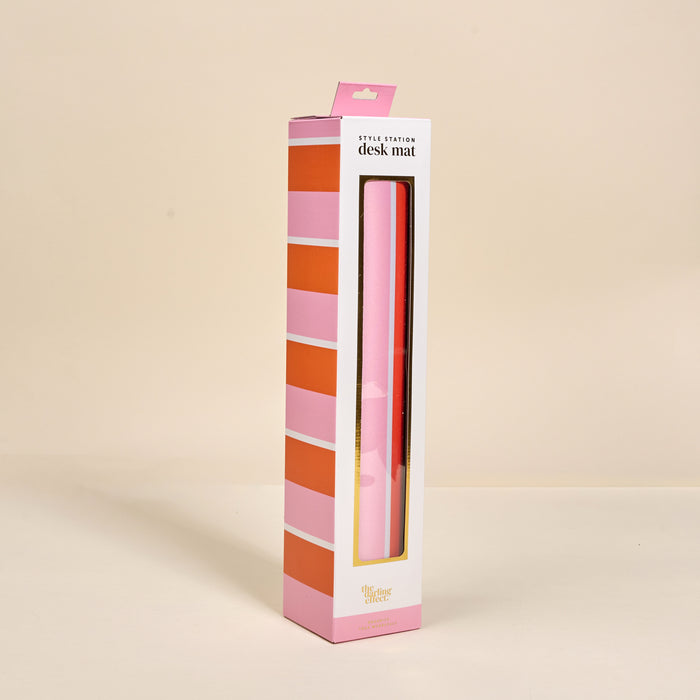 The Darling Effect Sicily Stripes Pink Style Station Desk Mat comes in striped pink packaging with a window cutout revealing the chic, non-slip mat inside—perfect for enhancing your workspace against any neutral background.