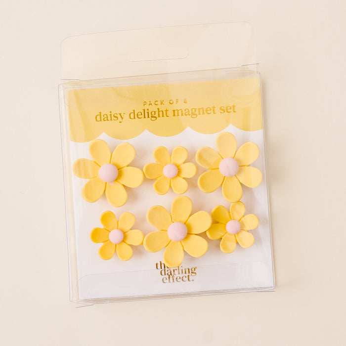 The Yellow Daisy Delight Magnet Set by the-darling-effect features six vibrant yellow daisy magnets with pink centers in a clear package. These magnets offer a strong hold, perfect for any surface.