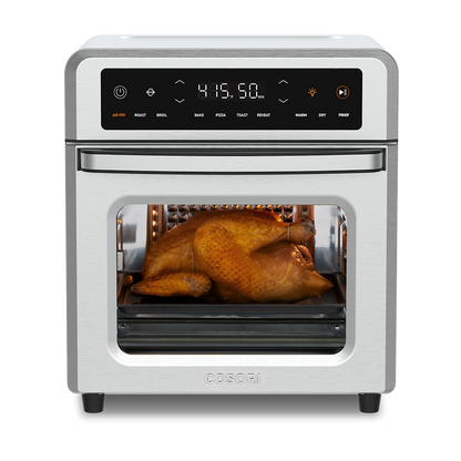 Cosori 13-Quart Air Fryer Oven with a whole roasted chicken cooking inside. Stainless steel finish