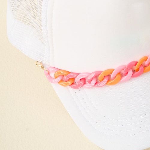 Close-up of The Darling Effect's Acrylic Sassy Trucker Hat Chain, featuring a white mesh trucker cap with a chunky pink and orange plastic chain along the brim. Shown against a simple light background.