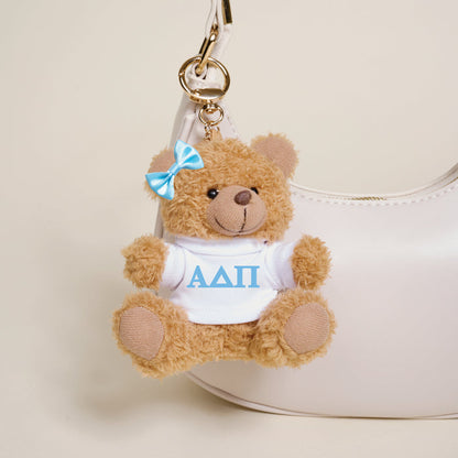 The Darling Effect’s Alpha Delta Pi Teddy Bear Bag Charm features a small brown bear with a blue bow and white shirt with blue Greek letters—an adorable accessory for your bag or the perfect Bid Day gift.