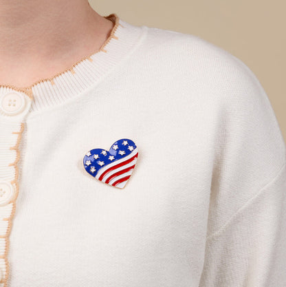 The Darling Effect’s Americana Heart Timeless Brooch, elegantly styled, is worn on a cream-colored cardigan.