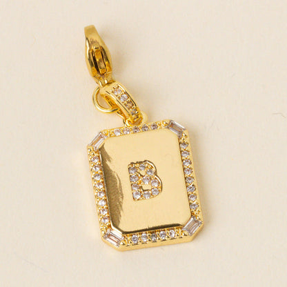 The B Jewelry Charm Initial Letter Gold by the-darling-effect features a gold-plated pendant with a B at the center, outlined in clear gemstones. Its decorative loop lets you easily personalize any chain with stylish flair.