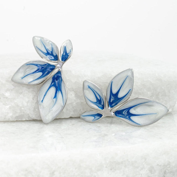 Pair of blue and white leaf-shaped earrings on a textured white surface