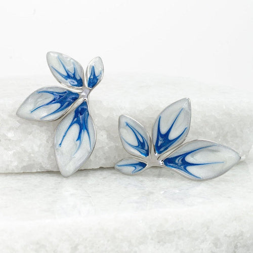 Pair of blue and white leaf-shaped earrings on a textured white surface