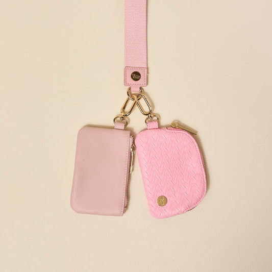 The Darling Effect’s Blush Dynamic Duo Pouch Luxe Wristlet features two pastel pink pouches—one smooth, one textured—on a matching lanyard with chic gold zippers and clasps, perfect for stylish, hands-free carrying.