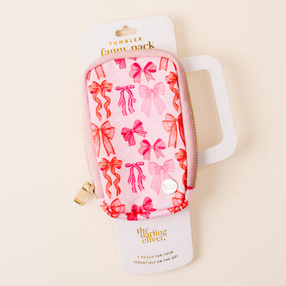 The Blushing Bows Tumbler Fanny Pack by the-darling-effect features a pink design with red and pink bow patterns and a zipper. It's shown on its packaging labeled "Tumbler Fanny Pack" and "the-darling-effect.