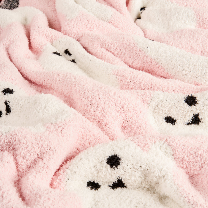 The Darling Effect Boo Crew Cozy Dreams Luxe Blanket features ultra-soft microfiber in pink and white, with adorable black outlined faces resembling seals or bears scattered across the cozy fabric.