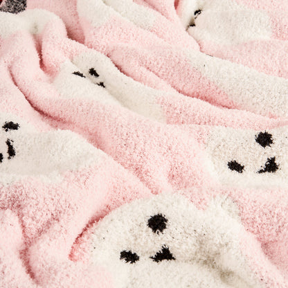 The Darling Effect Boo Crew Cozy Dreams Luxe Blanket features ultra-soft microfiber in pink and white, with adorable black outlined faces resembling seals or bears scattered across the cozy fabric.