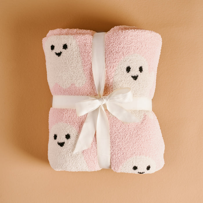 Folded pink and white towels with smiling cartoon ghosts, tied with a white ribbon on a beige surface—perfectly complement The Darling Effect’s Boo Crew Cozy Dreams Luxe Blanket for an ultra-soft touch.