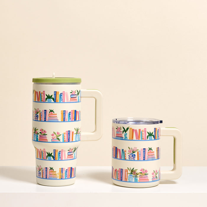 Two cream-colored Book Shelfie 20 oz Lifestyle Flip Straw Tumblers by The Darling Effect feature vibrant bookshelf and plant designs. Each insulated stainless steel tumbler keeps drinks at the perfect temperature.