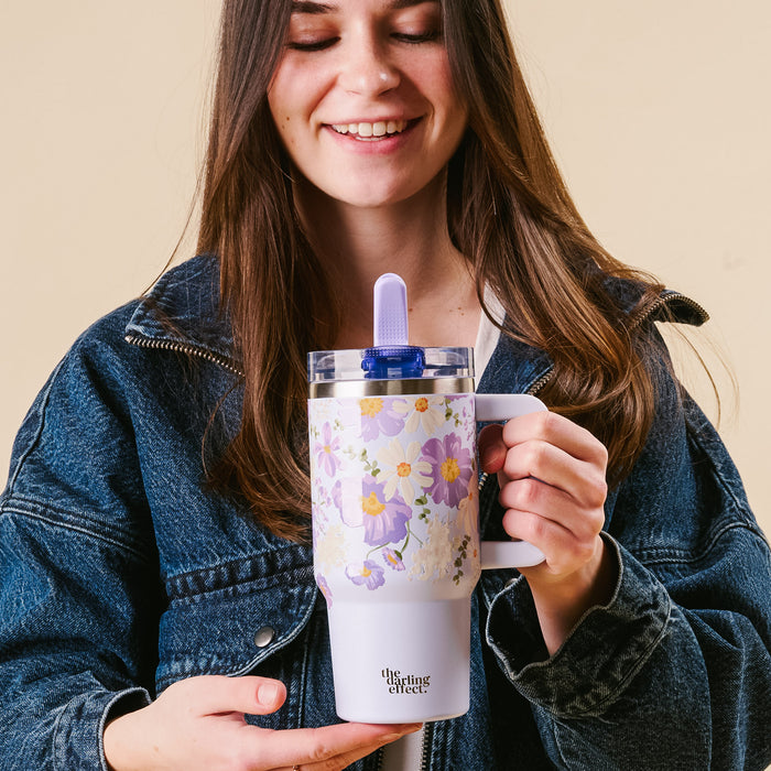 A woman smiles with her eyes closed while holding the-darling-effect's Bouquet Beauty Purple 20 oz Lifestyle Flip Straw Tumbler.