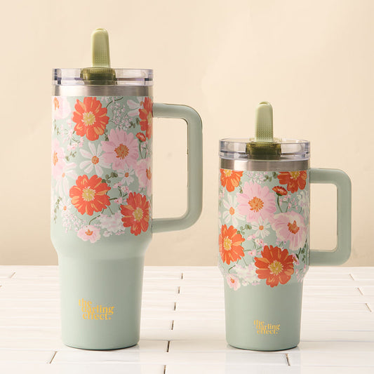 Two Bouquet Beauty Sage 40 oz Lifestyle Flip Straw Tumblers by the-darling-effect, leak-resistant with large handles, green straws, clear lids, and floral patterns in orange, white, and pink are shown on a white tiled surface.