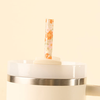 The the-darling-effect Bouquet Beauty Sage 40 oz Tumbler Straw Set features a BPA-free reusable straw with an orange floral pattern, standing upright in the lid of a white insulated tumbler against a cream background.