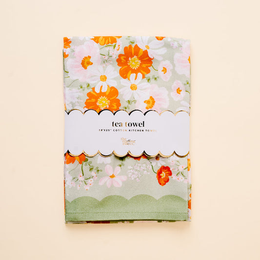 The Bouquet Beauty Sage Tea Towel by the-darling-effect is a folded cotton towel with a sage green floral print in orange, pink, and white, wrapped in a scallop-edged label reading “tea towel 18x25 by The Darling Effect.”.