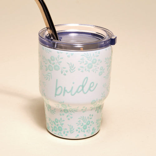 The Darling Effect Bride 2 oz Tiny Tumbler features white insulation, a clear lid, metal straw, light blue floral designs, and "bride" in script—perfect for keeping drinks at the ideal temperature for every celebration.