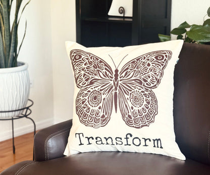 Hand-sewn & hand-screen printed decorative 20" x 20" cotton canvas pillow with boho-style butterfly design and the word Transform. Made by Survivors.