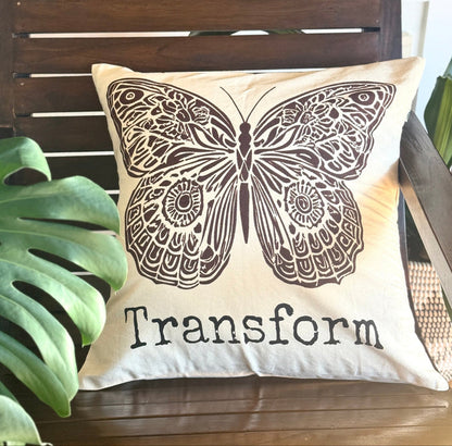 Hand-sewn & hand-screen printed decorative 20" x 20" cotton canvas pillow with boho-style butterfly design and the word Transform. Made by Survivors.