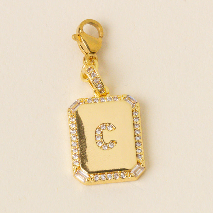 The-darling-effect’s C Jewelry Charm Initial Letter Gold features a gold-plated charm with beveled edges, cubic zirconia accents, a raised letter C center, and a lobster clasp for easy attachment to any initial letter jewelry collection.