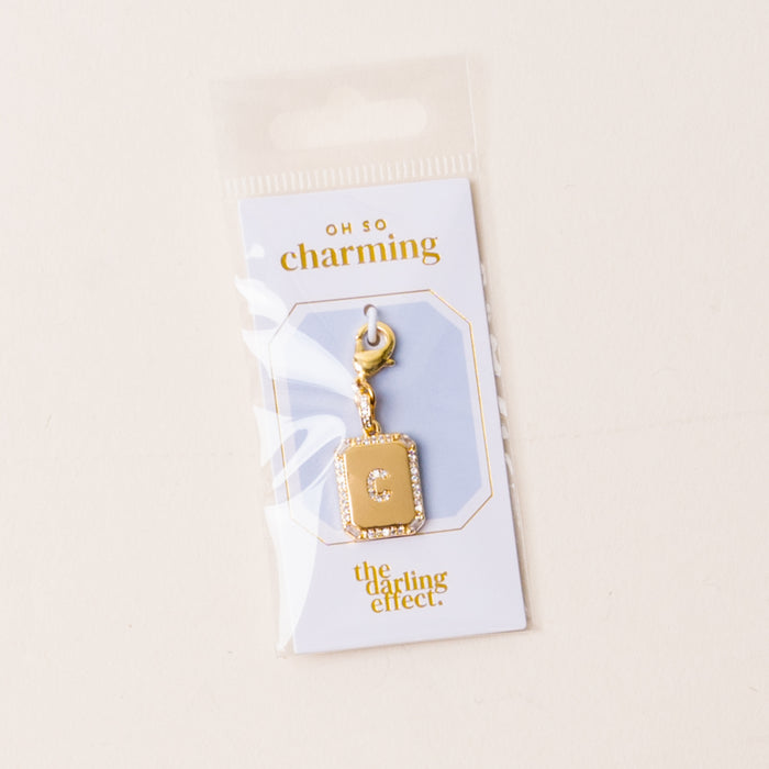 The-darling-effect C Jewelry Charm Initial Letter Gold features a gold-plated square charm with clasp, attached to an OH SO charming card—ideal for personalized jewelry. Packaged in a clear sleeve against a light background.