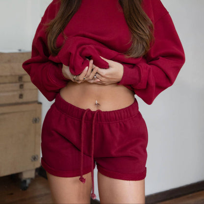 Woman wearing a red tracksuit standing indoors with a neutral background