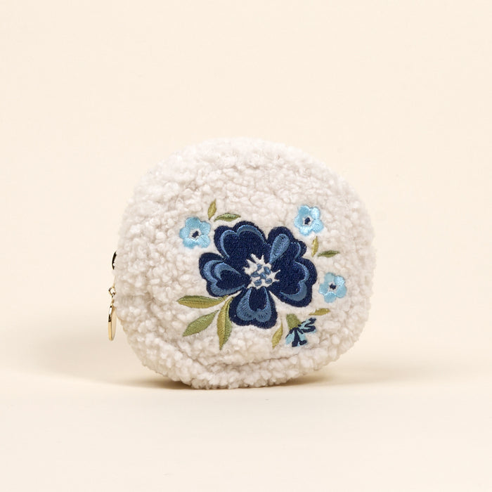 The Circle Dainty Floral Navy Teddy Pouch by the-darling-effect is a round, white sherpa zip pouch with a keyring, embroidered with blue and light blue flowers and green leaves—a perfect accessory for on-the-go organization.