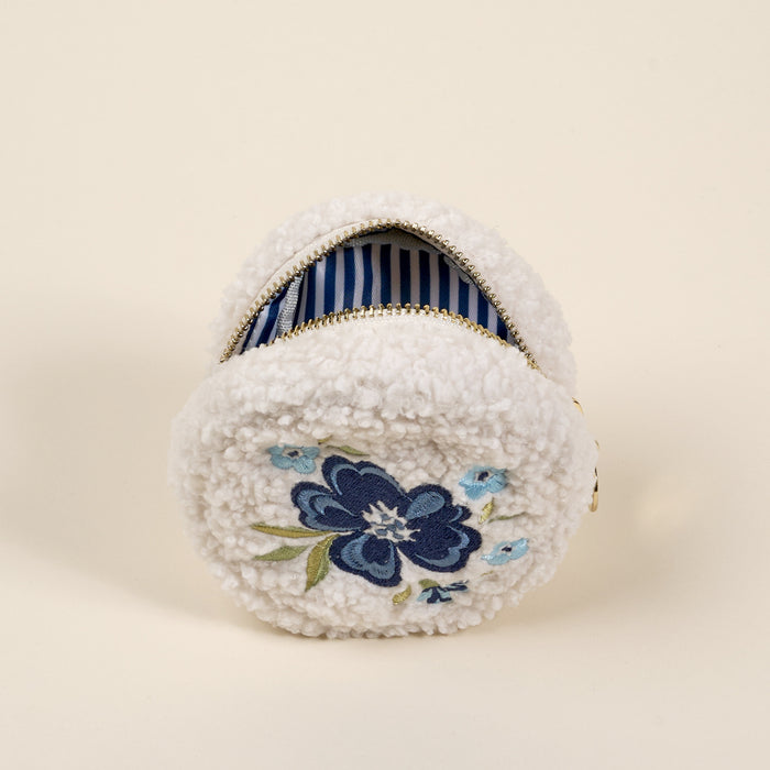 The Circle Dainty Floral Navy Teddy Pouch by the-darling-effect features white fuzzy sherpa, blue floral embroidery, and a striped interior—an ideal addition to your teddy pouches accessory set.