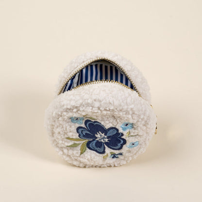 The Circle Dainty Floral Navy Teddy Pouch by the-darling-effect features white fuzzy sherpa, blue floral embroidery, and a striped interior—an ideal addition to your teddy pouches accessory set.
