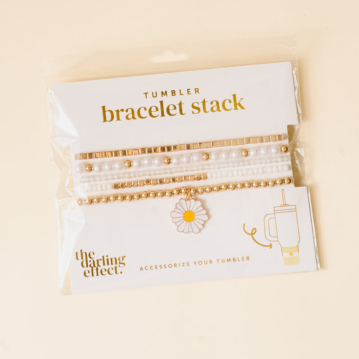 The Daisy Dream Tumbler Bracelet Stack by the-darling-effect features gold and pearl-like beads, white bands, and a daisy charm. Perfect tumbler accessories for your 40 oz tumbler. Label: Tumbler bracelet stack & the-darling-effect.