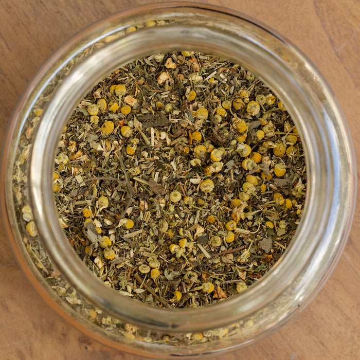 Glass jar filled with dried herbs and flowers on a wooden surface