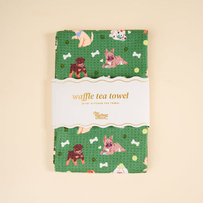 The Dog Days Waffle Tea Towel by The Darling Effect features cartoon dogs and bones, is absorbent and decorative, and comes folded with a label that reads "waffle tea towel" and "The Darling Effect." Great for your kitchen or as a cute home accent.