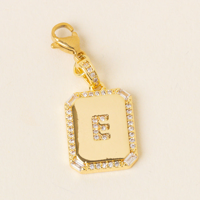 The-darling-effect's E Jewelry Charm Initial Letter Gold features a gold-plated brass pendant with clear gemstone accents, a raised letter E, and a gold lobster clasp—ideal for fans of personalized jewelry.