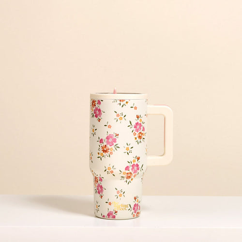 The-darling-effect Endless Daydream Cream 20 oz Lifestyle Flip Straw Tumbler features a pink floral pattern, insulated stainless steel build, and cream handle, shown on a cream background.