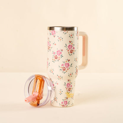 The-darling-effect’s Endless Daydream Cream 40 oz Lifestyle Flip Straw Tumbler features a tall, white body with pink floral patterns, a matching handle, and a transparent lid with an orange slider and pink flip straw for leak-resistance.