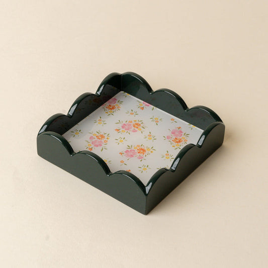 The Endless Daydream Cream Scallop Trinket Tray by the-darling-effect features scalloped edges and a floral pattern, making it perfect as a stylish napkin holder or jewelry organizer on a light beige surface.