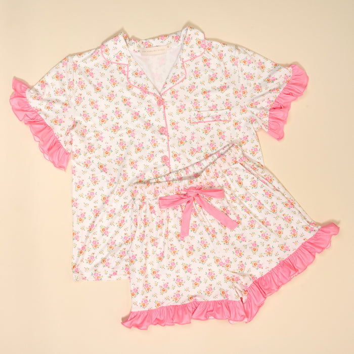 The Darling Effect's Endless Daydream Cream Slumber Party Pajama Shorts Set features ultra-soft white fabric, pink floral print, ruffled edges, and a pink bow detail—perfect for your next pajama party.