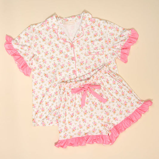 The Darling Effect's Endless Daydream Cream Slumber Party Pajama Shorts Set features ultra-soft white fabric, pink floral print, ruffled edges, and a pink bow detail—perfect for your next pajama party.
