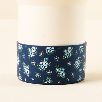 The-darling-effect Endless Daydream Navy Tumbler Silicone Boot is a white cylinder with a navy blue floral-patterned base, offering tumbler protection and helping prevent dents.