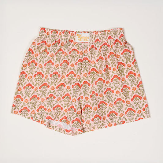 Everbloom Dusty Rose All Day Boxer Shorts by The Darling Effect feature a floral orange and red print with green leaves on light pink, an elastic waistband, and breathable fabric, shown laid flat on a white surface for a comfy look.