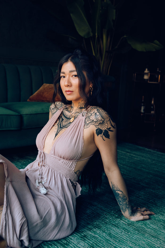 Woman in a pink dress with lace details sitting on a green couch.