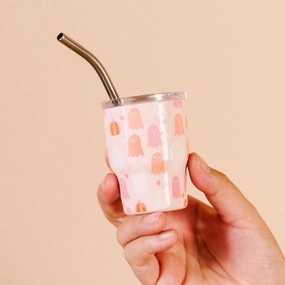 A hand holds The Darling Effect Ghost Party 2 oz Tiny Tumbler—a small pink Halloween cup featuring a ghost pattern and a silver straw.