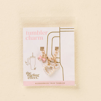 Add sparkle to your tumbler with the-darling-effect’s Glamour Tumbler Charm—featuring a gold chain, pink gem, pink bow, and white beaded heart! Packaged with "tumbler charm" and a cup graphic for stylish flair.