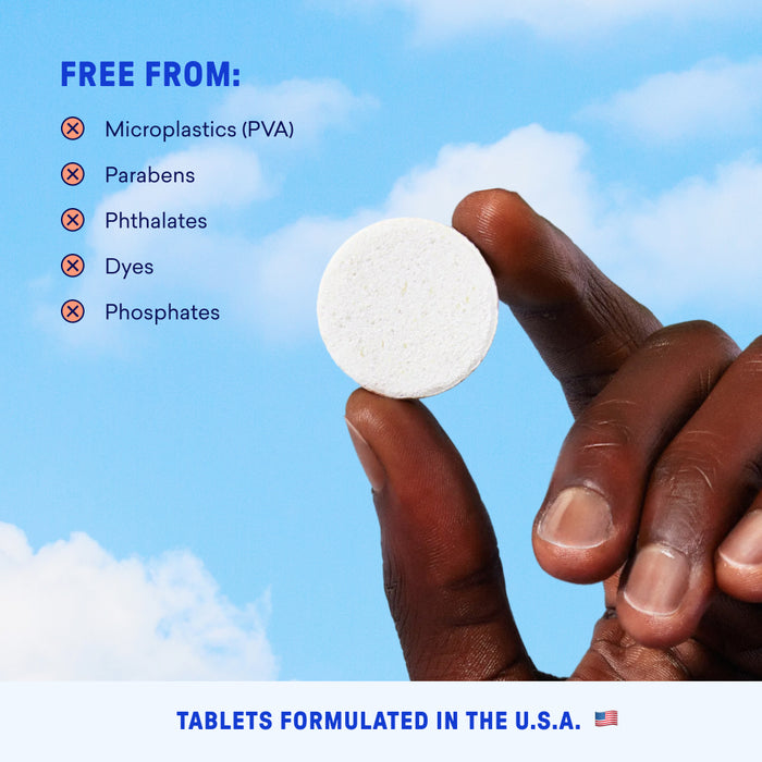 A hand holds the Hand Soap Starter 2-Pack tablet against a blue sky. Free from microplastics (PVA), parabens, phthalates, dyes & phosphates. Perfect for plastic-free hand soap. Caption: “Tablets manufactured in the U.S.A.”.