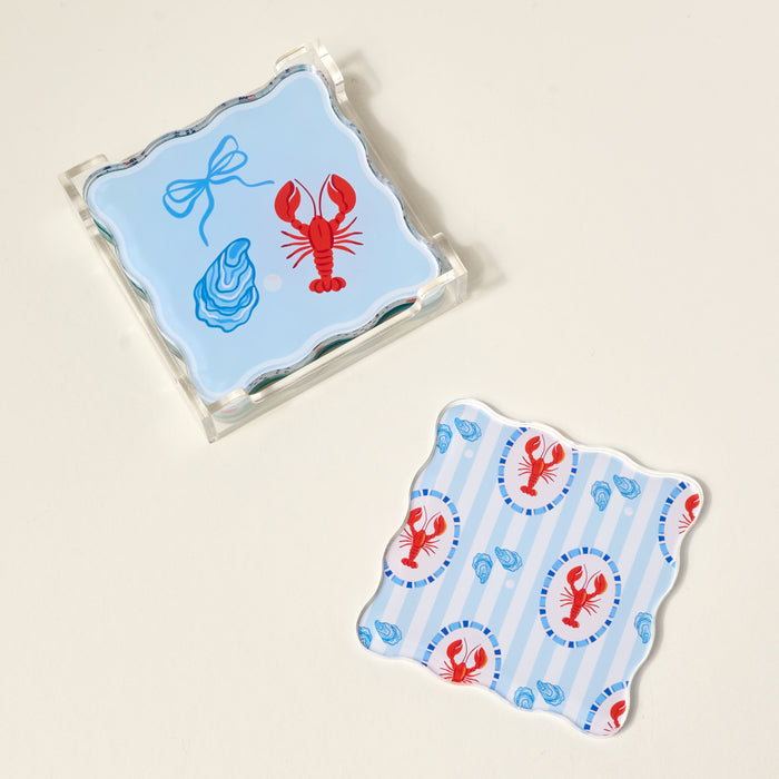 The Darling Effect’s Harbor House Table Talk Acrylic Coaster Set includes two square scalloped coasters: one with a blue bow, red lobster, and oyster on light blue; the other with lobsters and oysters on stripes—perfect for stylish table décor.