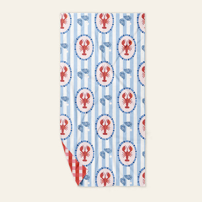 The Darling Effect Harbor House XL Quick-Dry Beach Towel features blue and white stripes, lobster designs with oyster shells, a red and white gingham underside, and sand-resistant microfiber—perfect for your next stylish seaside adventure.