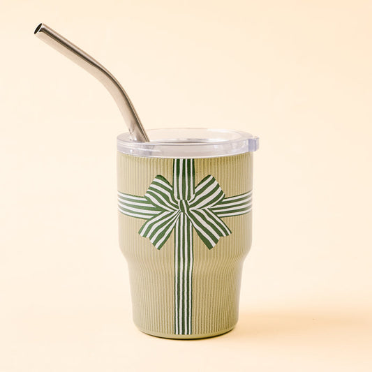 The Darling Effect Holiday Gift Bow Green 2 oz Tiny Tumbler features a metal straw, clear lid, and green striped bow on light beige—perfect for festive sipping this holiday season.